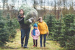 © Irina Schmidt - Happy family, man and two children with Christmas tree on fir tree cutting plantation. Preschool girl, kid boy and father choosing, cut and felling own xmas tree in forest, family tradition in Germany
