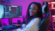 © Maksym - A happy young Blasian African American woman, fully engaged in a virtual team meeting from her modern home office. Her sleek setup includes a large monitor, keyboard, and comfortab