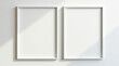 © Evgen - Pair of simple white frames arranged together on a monochromatic wall, photographed from afar