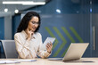 © Liubomir - Young woman in modern office checking tablet for work. Professional attire, focused on screen, engaged in digital communication. Represents technology, productivity, business environment.