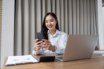 Professional Businesswoman Using Mobile and Laptop in Modern Office Setting for Communication and Productivity