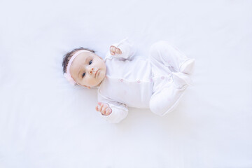 baby girl smiling on the bed on a white isolated background on a cotton bed, falling asleep or waking up in the morning, cute newborn little baby at home close-up