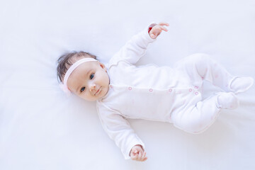 baby girl smiling on the bed on a white isolated background on a cotton bed, falling asleep or waking up in the morning, cute newborn little baby at home close-up