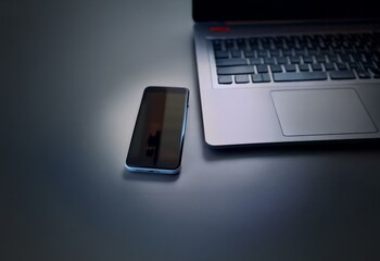 Aufkleber - A laptop and smartphone lie on a gray surface, the laptop's keyboard is out of focus.