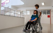 © Malik Nalik - A happy diverse students in university hallway, a classmate pushing a friend in a wheelchair as they walk down the school corridor or male patient smiling with friendly caregiver in hospital corridor.