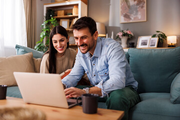 Couple collaborating on new project using laptop and tablet computers while working from home