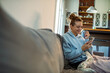 © Davor - Young adult woman using smartphone on the sofa at home