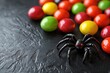 © peerasak - A colorful arrangement of candy with a plastic spider, creating a fun and spooky atmosphere, perfect for Halloween.