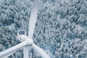 wind turbine close-up. aerial drone view of wind turbine in winter landscape with snow covered trees