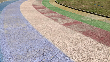 A colorful walking path in a park or public space. A colorful, curved pathway with rainbow-colored stripes