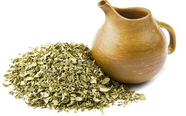 Dried herbs spilling from a brown ceramic jug accompanied by a natural wooden table setting