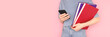 © rorygezfresh - Banner with student girl holding books in her hands and use smartphone. Back to school concept in front of pink background.
