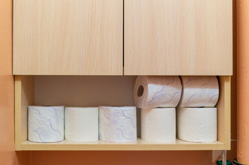 A wooden cabinet with toilet paper on it. The toilet paper is white and blue