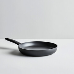 Black frying pan on a light gray surface with a smooth texture.