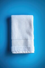 Wall Mural - A clean white towel lying flat on a bright blue surface