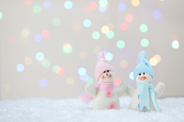 Wall Mural - Cute snowmen against beige background with blurred lights, bokeh effect