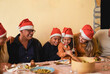 © Sabrina - Happy latin family celebrating Christmas with dinner together at home on patio wearing santa claus hats - Festive holiday event and multi generational people concept - Soft focus on the children