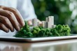© Stone Story - Hand arranging a miniature model of a green city landscape, highlighting urban planning and sustainability concepts.