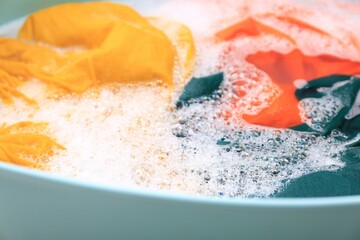 Canvas Print - Basin with colorful clothes in suds, closeup. Hand washing laundry