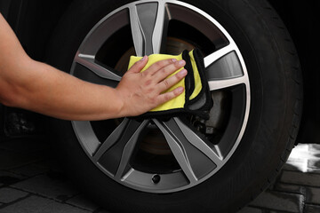 Wall Mural - Man wiping car wheel with yellow rag, closeup