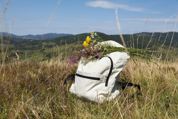 Wall Mural - Bouquet of beautiful flowers and backpack in mountains outdoors