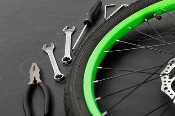 Wall Mural - Bicycle wheel and tools on black background, closeup