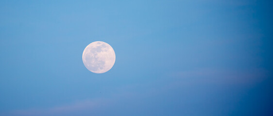 Full moon in blue sky. Supermoon is an astronomical event. Close-up of moon in evening or night sky.