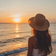 © Vikarest - A serene sunset view with a woman in a hat gazing at the ocean waves.