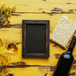 © PuriStudio - festive table setting featuring blank photo frame, wine bottle, wine glasses, and matzah, perfect for holiday celebration. vibrant yellow background adds cheerful touch