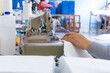 © Alexandermoam - Manos expertas cosiendo tela blanca en una máquina overlock, Detalle de una operación de costura en una fábrica textil
