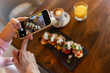 © Mediteraneo - Woman influencer taking pictures of food in a restaurant. Social media. Food and drink concept.