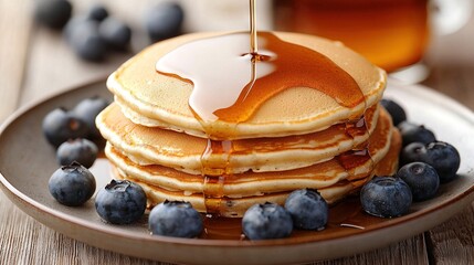 Wall Mural -   Blueberries and syrup drizzle on a plate with stacked pancakes