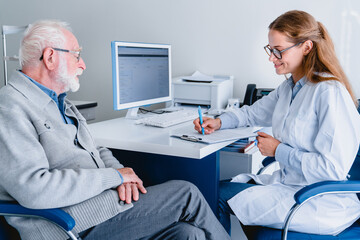 Side view of female doctor prescribing medicines to her mature male patient sitting at the table