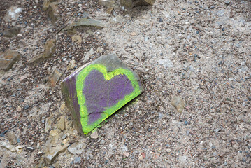 heart painted with neon color on a stone, on a mountain path