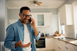 © Drazen - Happy man making  phone call in kitchen.