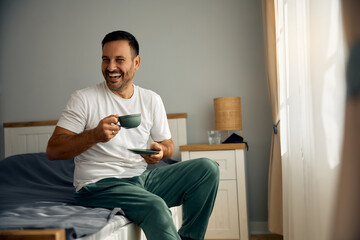 Wall Mural - Happy man having cup of coffee in bedroom in morning.