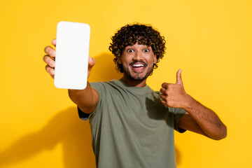 Sticker - Photo of good mood guy dressed khaki t-shirt demonstrate smartphone touchscreen empty space show thumb up isolated on yellow color background