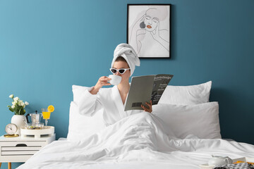 Wall Mural - Morning of young woman with magazine drinking coffee in bedroom