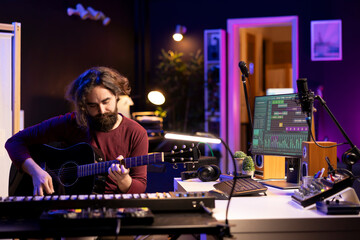 Leinwandbilder - Young music producer playing guitar and creating songs using digital daw software. Musician singer recording music in home studio, audio engineer mixing pop rock tracks using modern equipment.