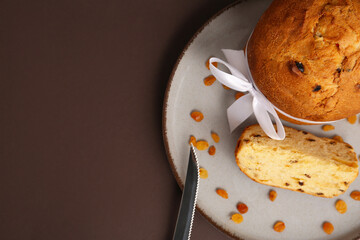 Poster - Panettone with white ribbon on plate on brown background. Top view