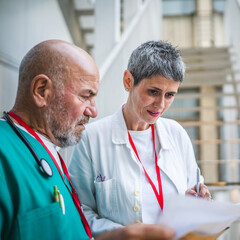 Two doctors check information from clipboard and document on staircase