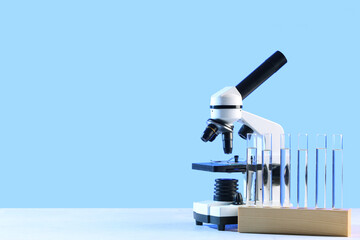 Holder with test tubes and modern microscope on white table