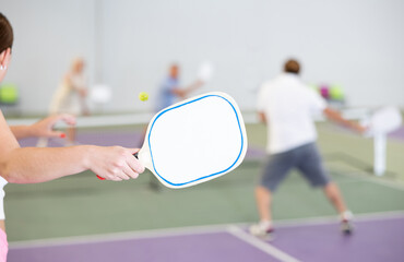 Wall Mural - Rear view of girl with white racket playing pickleball tennis at court