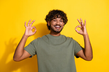 Poster - Photo of positive guy with wavy hair dressed khaki t-shirt fingers showing okey approve nice work isolated on yellow color background