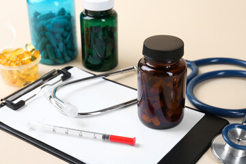 Canvas Print - Pharmacist. Pills in plastic bottles, clipboard, syringe and stethoscope on beige background