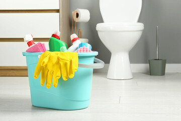 Poster - Bucket with different toilet cleaners, rag, sponge and gloves on floor in bathroom