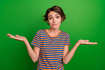 Sticker - Portrait of charming clueless person shrug shoulders arms hold empty space solution isolated on green color background