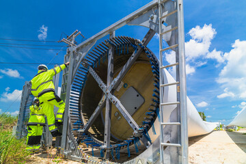 two engineers in safety gear inspecting a wind turbine blade section on a construction site. they ex