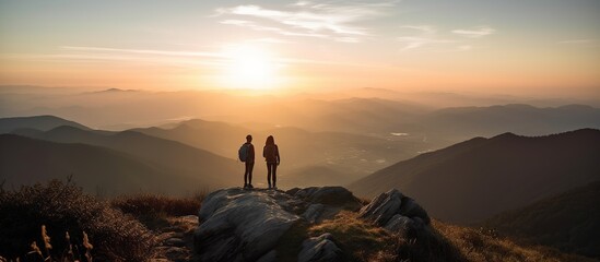 Silhouettes of Two Hikers at Sunrise in the Mountains