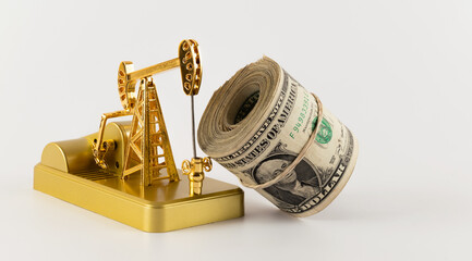 Miniature gold oil pump and rolled up stack of $1 bills